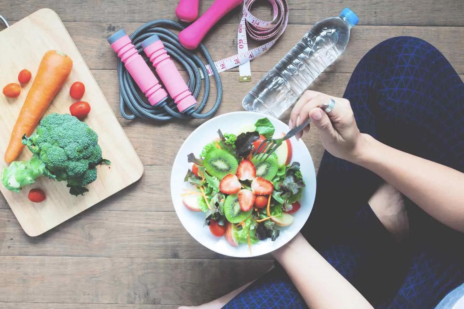 Bowl of salad beside vegetables, a jump rope and a water bottle